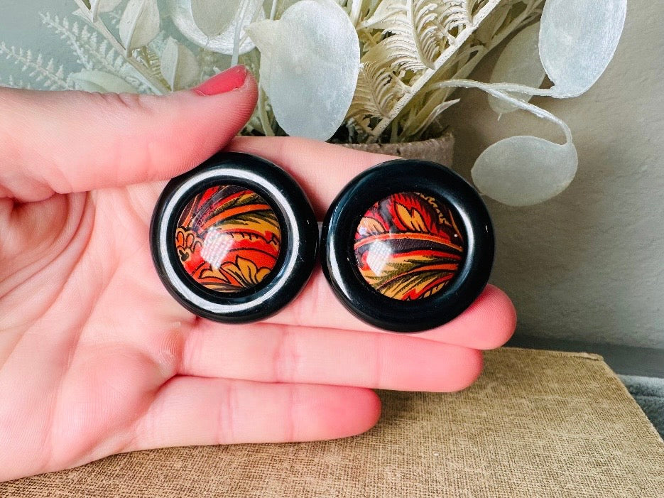 These big and bold 1980s acrylic earrings are so fun. Oversized circles with a solid black border and colorful mottled red and orange paisley printed center- pierced style. Great vintage condition- please see pics. More fun vintage pairs available!
Dimensions: about 1.25" diameter See additional pics for visual reference.