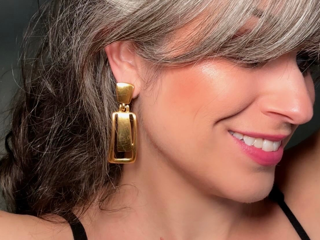 These Anne Klein vintage matte gold designer earrings are spectacular. Full of 1980s bold glamour, these clip ons have a satin gold finish and a geometric design. These vintage dangle earrings are bold and elegant, with curved square posts and rectangular drops with a cut out hollow border. These are big and incredibly well made in a satin matte gold finish. Clip on style, easy to wear and in great vintage condition. Highly sought after designer vintage.