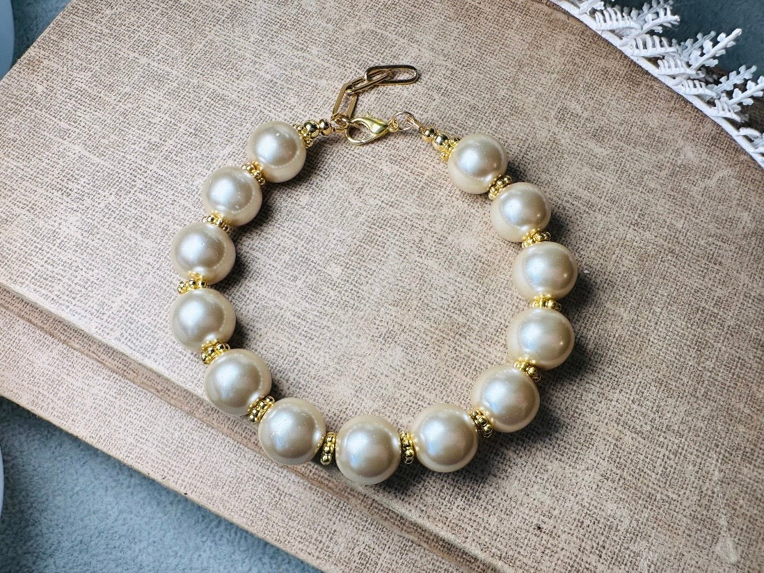 This classic pearl bracelet is handmade with gorgeous champagne pearls, gold filigree accents, and 18K hardware. The gold accents paired with the creamy champagne pearls are a classic and timeless design. This bracelet looks fantastic worn alone- or stack it with others to make a statement. This bracelet is made to order. Please select your desired base length at check out- a 1.5" extension will be added to easily customize the fit. Lobster clasp closure. A beautiful pearl bracelet- matching earrings are