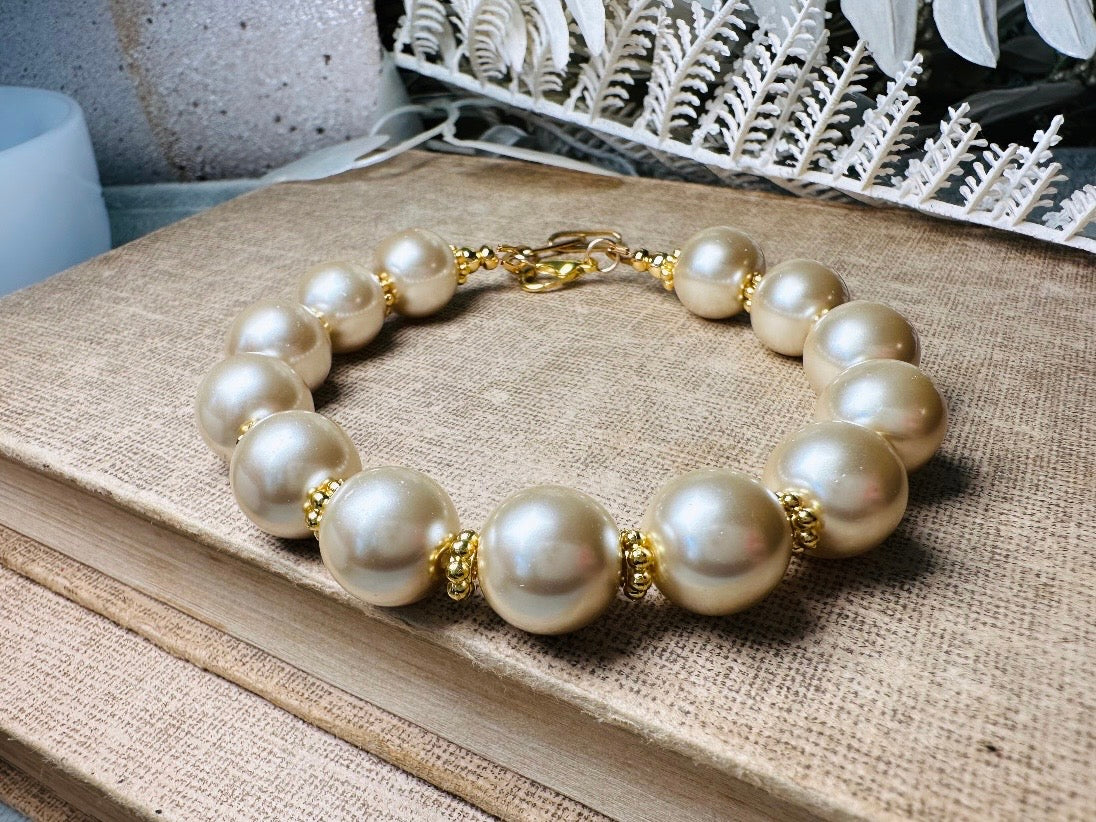 This classic pearl bracelet is handmade with gorgeous champagne pearls, gold filigree accents, and 18K hardware. The gold accents paired with the creamy champagne pearls are a classic and timeless design. This bracelet looks fantastic worn alone- or stack it with others to make a statement. This bracelet is made to order. Please select your desired base length at check out- a 1.5" extension will be added to easily customize the fit. Lobster clasp closure. A beautiful pearl bracelet- matching earrings are