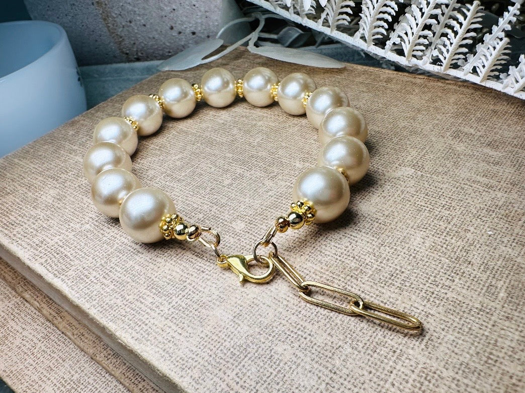 This classic pearl bracelet is handmade with gorgeous champagne pearls, gold filigree accents, and 18K hardware. The gold accents paired with the creamy champagne pearls are a classic and timeless design. This bracelet looks fantastic worn alone- or stack it with others to make a statement. This bracelet is made to order. Please select your desired base length at check out- a 1.5" extension will be added to easily customize the fit. Lobster clasp closure. A beautiful pearl bracelet- matching earrings are