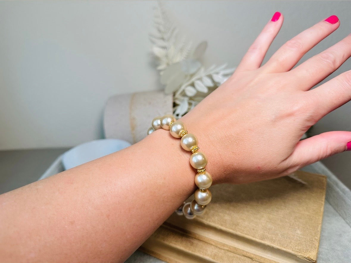 This classic pearl bracelet is handmade with gorgeous champagne pearls, gold filigree accents, and 18K hardware. The gold accents paired with the creamy champagne pearls are a classic and timeless design. This bracelet looks fantastic worn alone- or stack it with others to make a statement. This bracelet is made to order. Please select your desired base length at check out- a 1.5" extension will be added to easily customize the fit. Lobster clasp closure. A beautiful pearl bracelet- matching earrings are