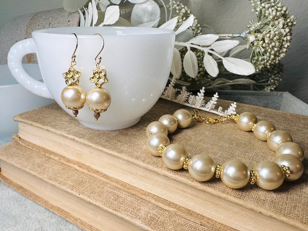 This classic pearl bracelet is handmade with gorgeous champagne pearls, gold filigree accents, and 18K hardware. The gold accents paired with the creamy champagne pearls are a classic and timeless design. This bracelet looks fantastic worn alone- or stack it with others to make a statement. This bracelet is made to order. Please select your desired base length at check out- a 1.5" extension will be added to easily customize the fit. Lobster clasp closure. A beautiful pearl bracelet- matching earrings are