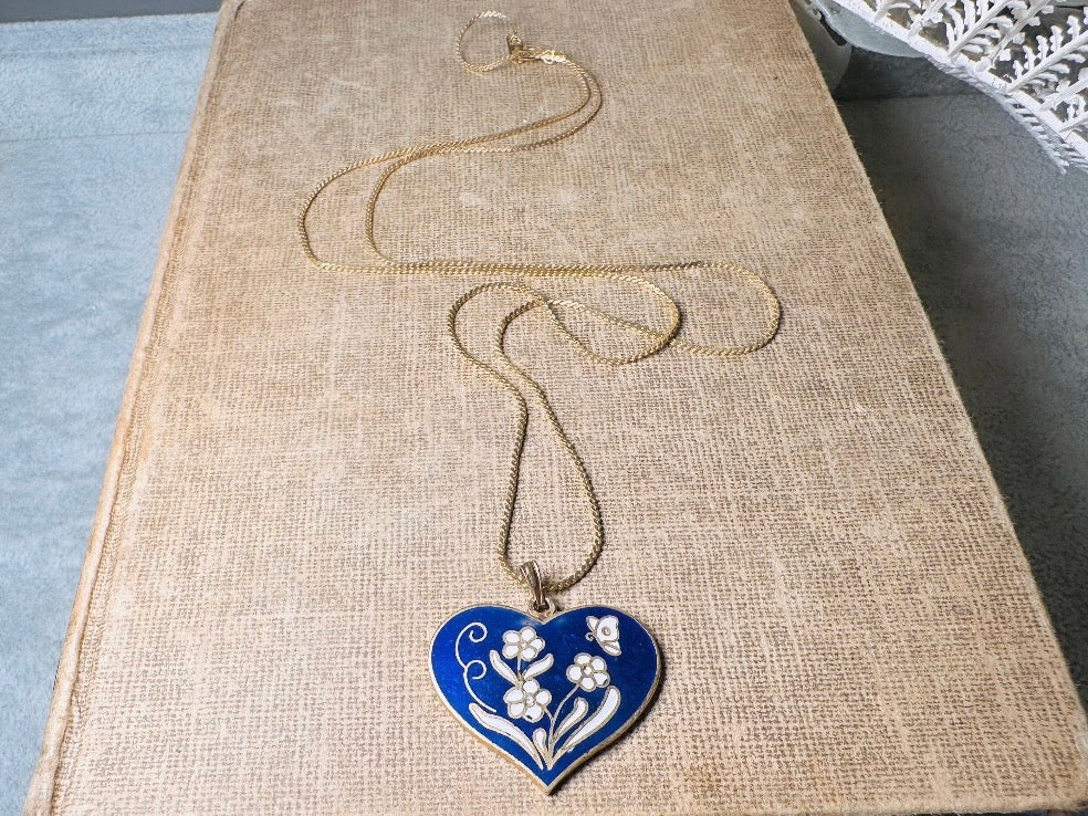 This vintage floral blue heart pendant necklace is so beautiful. Featuring a deep cobalt blue enameled heart pendant on long fine gold tone chain. This vintage blue heart necklace is romantic and whimsical- featuring white flowers trimmed in gold. Great for layering with others. Arrives beautifully[packaged and ready for gift giving.
Dimensions: pendant is 1" x 1.15" chain is 24" long