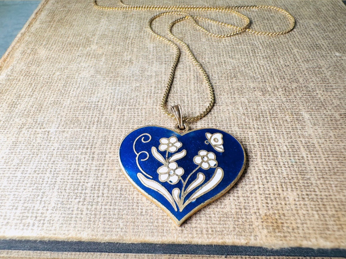 This vintage floral blue heart pendant necklace is so beautiful. Featuring a deep cobalt blue enameled heart pendant on long fine gold tone chain. This vintage blue heart necklace is romantic and whimsical- featuring white flowers trimmed in gold. Great for layering with others. Arrives beautifully[packaged and ready for gift giving.
Dimensions: pendant is 1" x 1.15" chain is 24" long