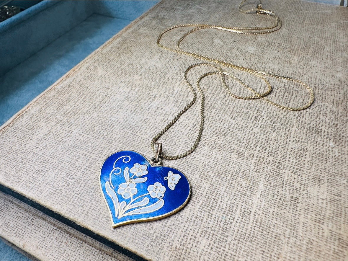 This vintage floral blue heart pendant necklace is so beautiful. Featuring a deep cobalt blue enameled heart pendant on long fine gold tone chain. This vintage blue heart necklace is romantic and whimsical- featuring white flowers trimmed in gold. Great for layering with others. Arrives beautifully[packaged and ready for gift giving.
Dimensions: pendant is 1" x 1.15" chain is 24" long