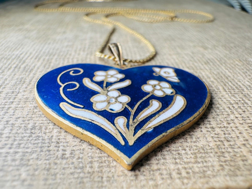 This vintage floral blue heart pendant necklace is so beautiful. Featuring a deep cobalt blue enameled heart pendant on long fine gold tone chain. This vintage blue heart necklace is romantic and whimsical- featuring white flowers trimmed in gold. Great for layering with others. Arrives beautifully[packaged and ready for gift giving.
Dimensions: pendant is 1" x 1.15" chain is 24" long