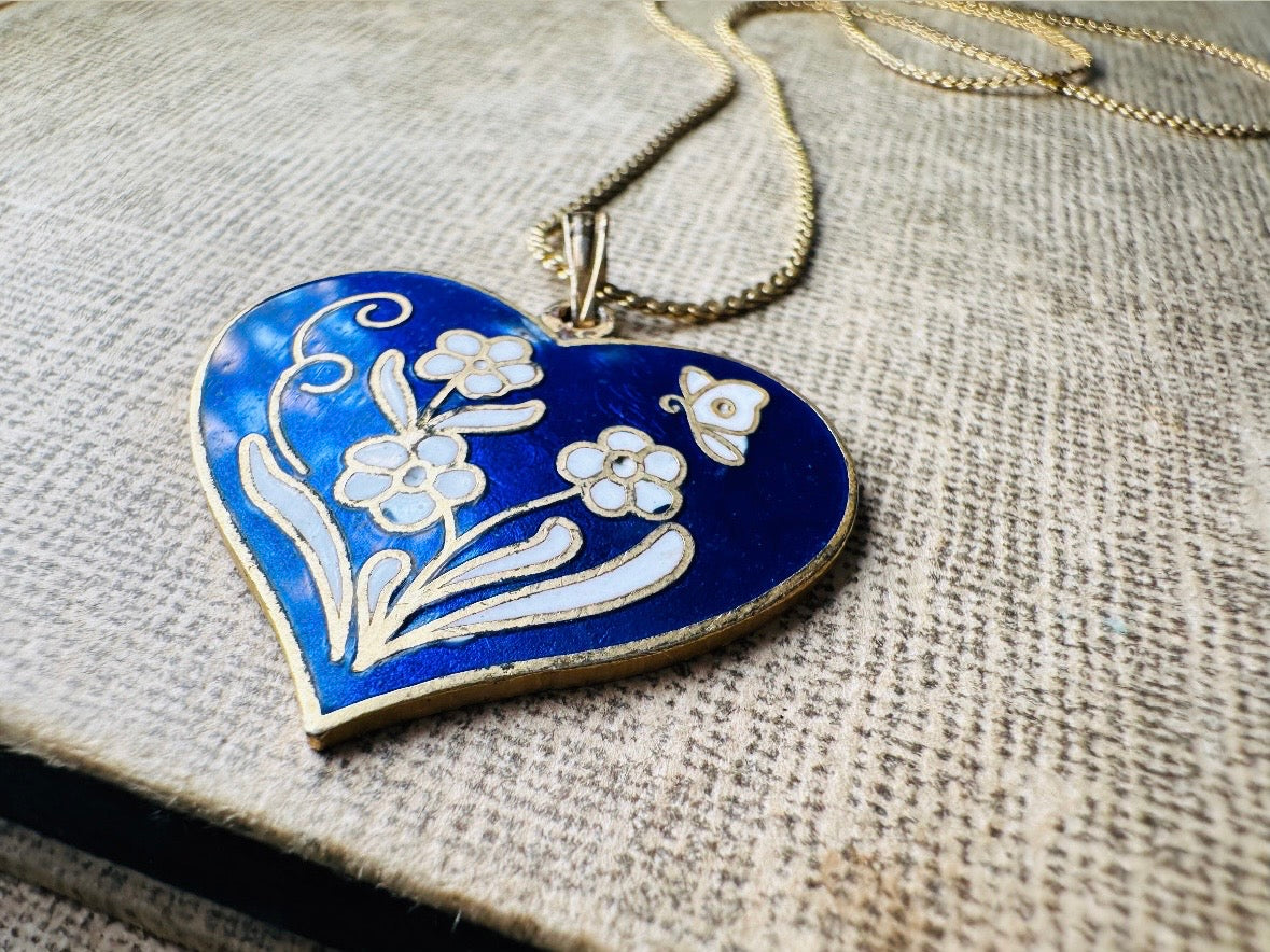 This vintage floral blue heart pendant necklace is so beautiful. Featuring a deep cobalt blue enameled heart pendant on long fine gold tone chain. This vintage blue heart necklace is romantic and whimsical- featuring white flowers trimmed in gold. Great for layering with others. Arrives beautifully[packaged and ready for gift giving.
Dimensions: pendant is 1" x 1.15" chain is 24" long