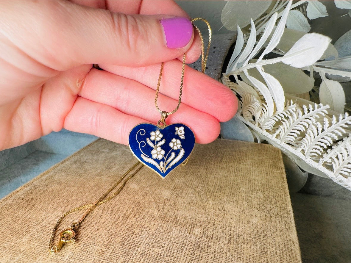 This vintage floral blue heart pendant necklace is so beautiful. Featuring a deep cobalt blue enameled heart pendant on long fine gold tone chain. This vintage blue heart necklace is romantic and whimsical- featuring white flowers trimmed in gold. Great for layering with others. Arrives beautifully[packaged and ready for gift giving.
Dimensions: pendant is 1" x 1.15" chain is 24" long