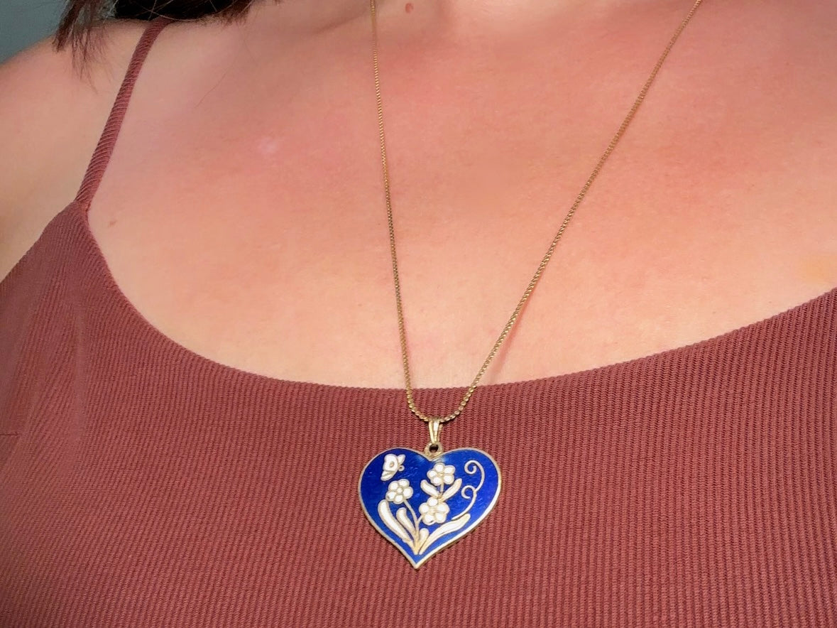 This vintage floral blue heart pendant necklace is so beautiful. Featuring a deep cobalt blue enameled heart pendant on long fine gold tone chain. This vintage blue heart necklace is romantic and whimsical- featuring white flowers trimmed in gold. Great for layering with others. Arrives beautifully[packaged and ready for gift giving.
Dimensions: pendant is 1" x 1.15" chain is 24" long
