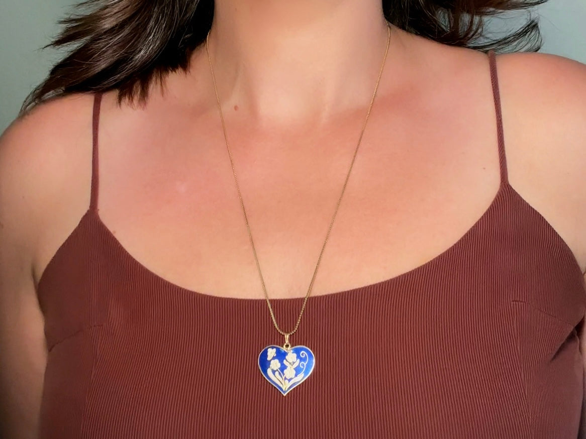 This vintage floral blue heart pendant necklace is so beautiful. Featuring a deep cobalt blue enameled heart pendant on long fine gold tone chain. This vintage blue heart necklace is romantic and whimsical- featuring white flowers trimmed in gold. Great for layering with others. Arrives beautifully[packaged and ready for gift giving.
Dimensions: pendant is 1" x 1.15" chain is 24" long