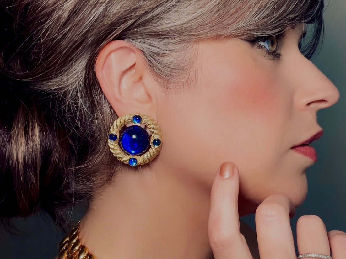 These vintage Park Lane gold rope earrings with cobalt blue cabochons are absolutely out of this world! Vibrant deep blue cabochons glow as they are surrounded by an intricate gold rope border that is accented with four more smaller blue jewels. These stones are so vibrant and vividly pop against their gold setting. Ultimate 80s mega star vibes, post style for pierced ears. Highly collectible signed designer pair in excellent vintage condition, no major flaws to note.