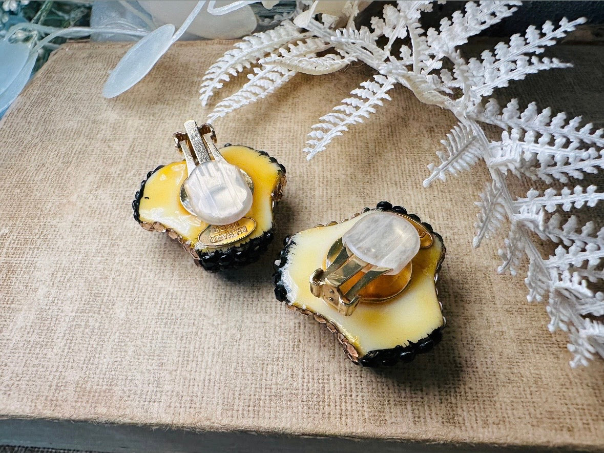 These glamorous vintage Richard Kerr cocktail earrings are spectacular. Sparkling black and gold pave set Swarovski crystals cover the entirety of the earrings, these statement earrings are the height of 80s glam. Featuring a sculptural 3d shape like a knot. The gold component is a rich topaz hue.
Clip on style, in great vintage condition.