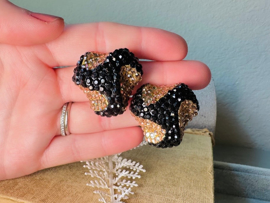 These glamorous vintage Richard Kerr cocktail earrings are spectacular. Sparkling black and gold pave set Swarovski crystals cover the entirety of the earrings, these statement earrings are the height of 80s glam. Featuring a sculptural 3d shape like a knot. The gold component is a rich topaz hue.
Clip on style, in great vintage condition.