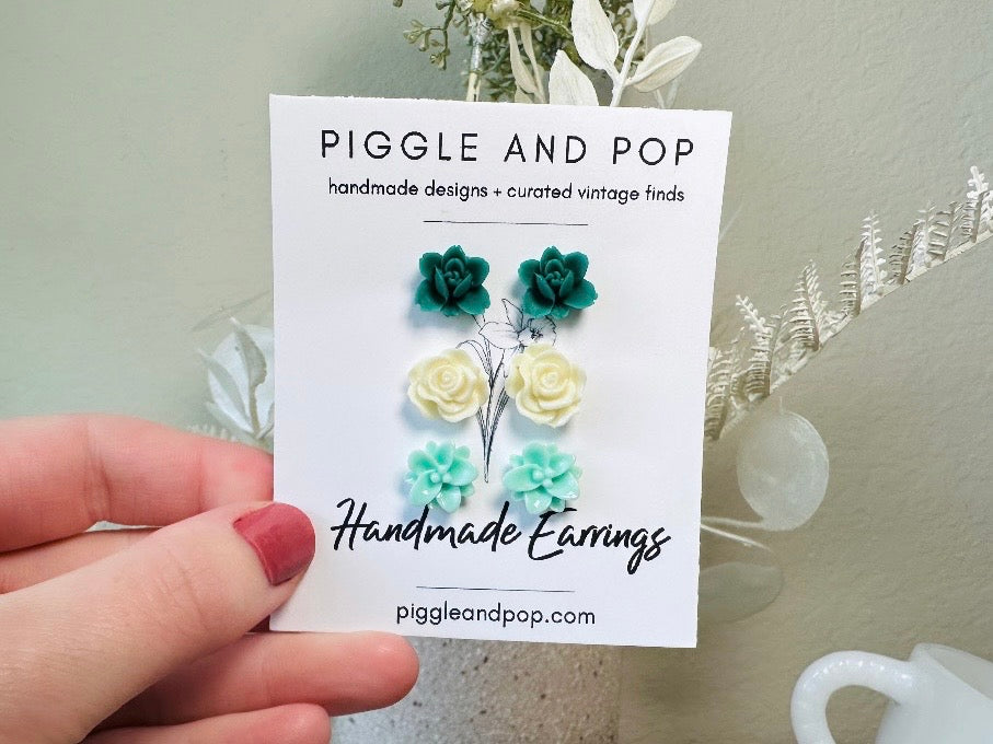 This green and mint flower stud earrings set is a wonderful addition to your jewelry box. This earring set features three pairs of resin flower earrings: emerald orchid earrings with a matte finish, creamy bloomed rose earrings and aqua lotus earrings. These pretty flower earrings feature hypoallergenic surgical steel posts and butterfly backs. Dressed up or down, they are perfect for any occasion!