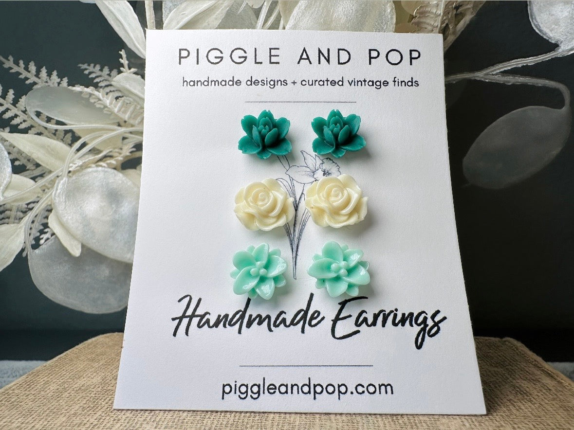 This green and mint flower stud earrings set is a wonderful addition to your jewelry box. This earring set features three pairs of resin flower earrings: emerald orchid earrings with a matte finish, creamy bloomed rose earrings and aqua lotus earrings. These pretty flower earrings feature hypoallergenic surgical steel posts and butterfly backs. Dressed up or down, they are perfect for any occasion!