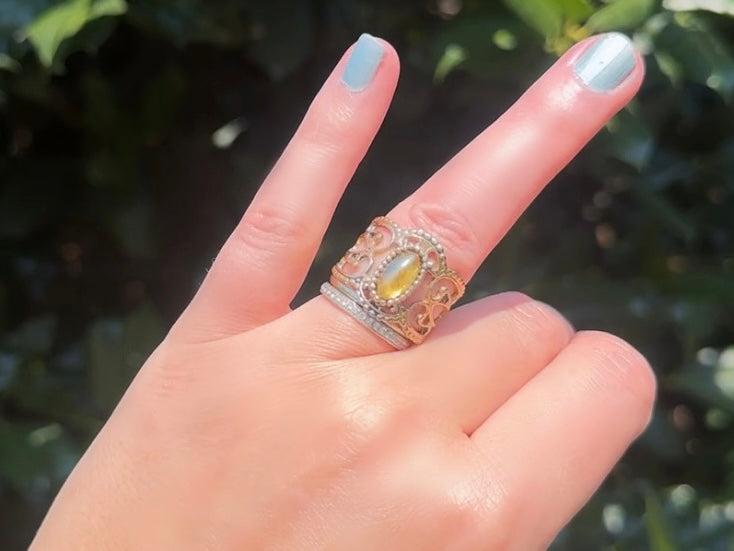 This 1970s Victorian revival vintage filigree ring is gorgeous. Featuring a faux fire opal cabochon stone set in a gold dotted bezel, the base of the ring is a beautiful open work lace filigree in an antique gold. High quality and strong filigree. Marked Sarah Coventry from 1970s.