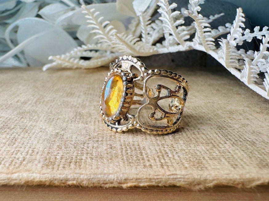 This 1970s Victorian revival vintage filigree ring is gorgeous. Featuring a faux fire opal cabochon stone set in a gold dotted bezel, the base of the ring is a beautiful open work lace filigree in an antique gold. High quality and strong filigree. Marked Sarah Coventry from 1970s.
