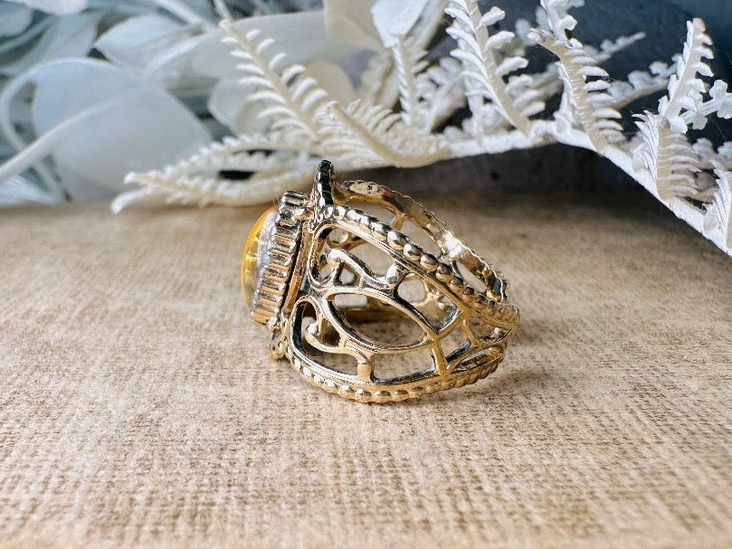 This 1970s Victorian revival vintage filigree ring is gorgeous. Featuring a faux fire opal cabochon stone set in a gold dotted bezel, the base of the ring is a beautiful open work lace filigree in an antique gold. High quality and strong filigree. Marked Sarah Coventry from 1970s.
