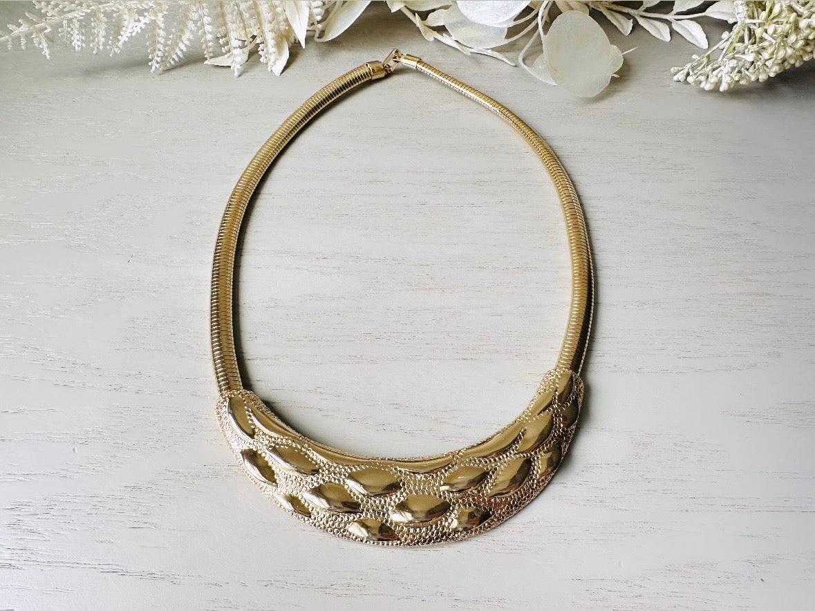 This gold omega necklace is a Park Lane signed designer vintage choker necklace from the 1980s. Featuring wide band gold snake chain with a textured raised geometric crescent bar, this gold collar necklace is bold and beautiful. In excellent vintage condition, signed Park Lane on back.