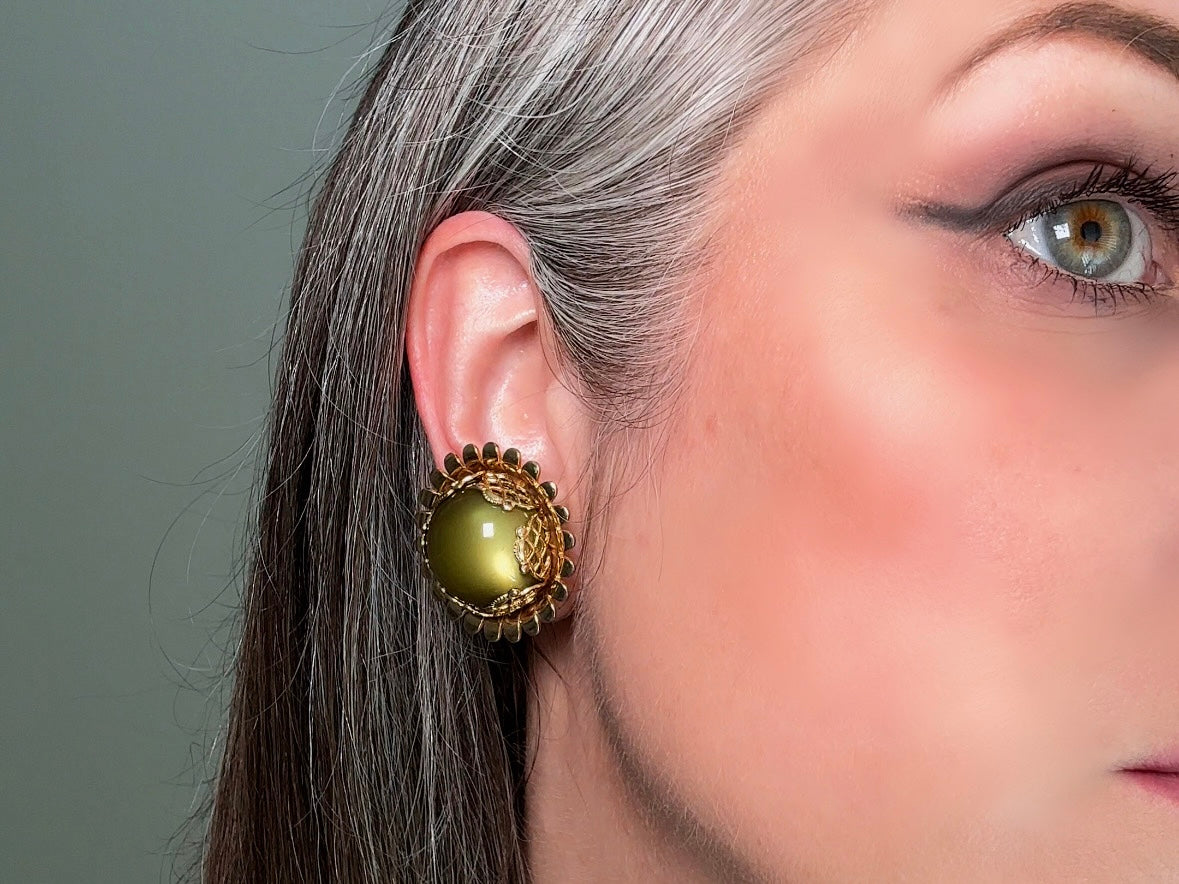 These gorgeous 1950s moonglow Caroline Emmons vintage earrings are stunning. Featuring glowing avocado green lucite cabochons set in a lacey gold open work bezel. These authentic 50s vintage earrings are gold tone base clip on style, signed on back. Their large size, incredible details and spectacular moon glow effect make them a unique collector's pair. Great vintage condition, no major flaws to note - please see pics. Such a stunning statement pair! Beautiful cocktail pair for the holidays.