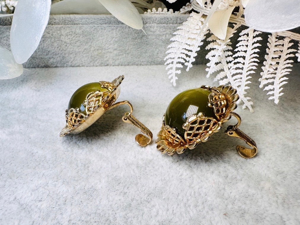 These gorgeous 1950s moonglow Caroline Emmons vintage earrings are stunning. Featuring glowing avocado green lucite cabochons set in a lacey gold open work bezel. These authentic 50s vintage earrings are gold tone base clip on style, signed on back. Their large size, incredible details and spectacular moon glow effect make them a unique collector's pair. Great vintage condition, no major flaws to note - please see pics. Such a stunning statement pair! Beautiful cocktail pair for the holidays.