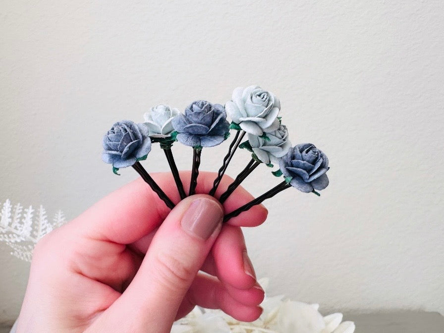 Six handmade rose hair pins with small grey paper flowers. The flowers are in shades of gray; three light silvery grey and three dark charcoal grey. The hair pins are dark bronze.