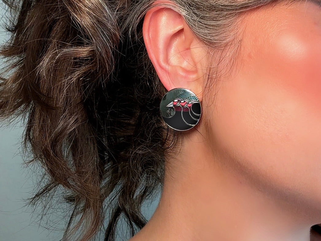 A pair of Laurel Burch vintage earrings titled "Celestial Birds". These post earrings are shiny silver with black and plum pink enamel of three birds lined up in a side profile. Laurel Burch is highly collectible, and these are so unique. Engraved with the the title "Celestial Birds" on the back of earrings along the the signature on the backs. Silver plated posts, excellent condition with very minor wear. They are about 1 inch big and available from Piggle and Pop. Modelled for size reference.