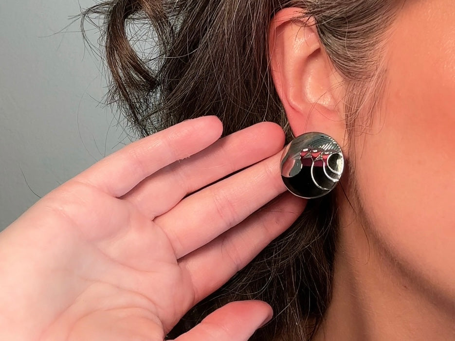 A pair of Laurel Burch vintage earrings titled "Celestial Birds". These post earrings are shiny silver with black and plum pink enamel of three birds lined up in a side profile. Laurel Burch is highly collectible, and these are so unique. Engraved with the the title "Celestial Birds" on the back of earrings along the the signature on the backs. Silver plated posts, excellent condition with very minor wear. They are about 1 inch big and available from Piggle and Pop.