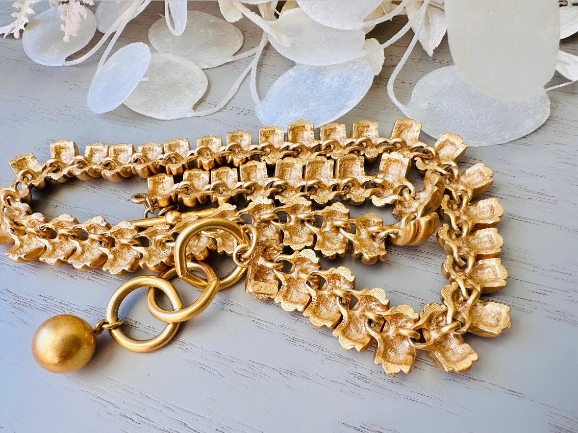 This vintage Anne Klein matte gold statement necklace is a beautiful classic satin gold collar necklace with articulated link segments.A signed AK piece, well known for superior quality and craftsmanship- this gold collar necklace is the perfect one to wear alone or pair with others for a spectacular stack. Toggle clasp at adjustable lengths.