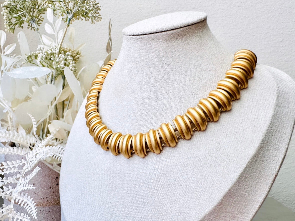 This vintage Anne Klein matte gold statement necklace is a beautiful classic satin gold collar necklace with articulated link segments.A signed AK piece, well known for superior quality and craftsmanship- this gold collar necklace is the perfect one to wear alone or pair with others for a spectacular stack. Toggle clasp at adjustable lengths. on display bust.