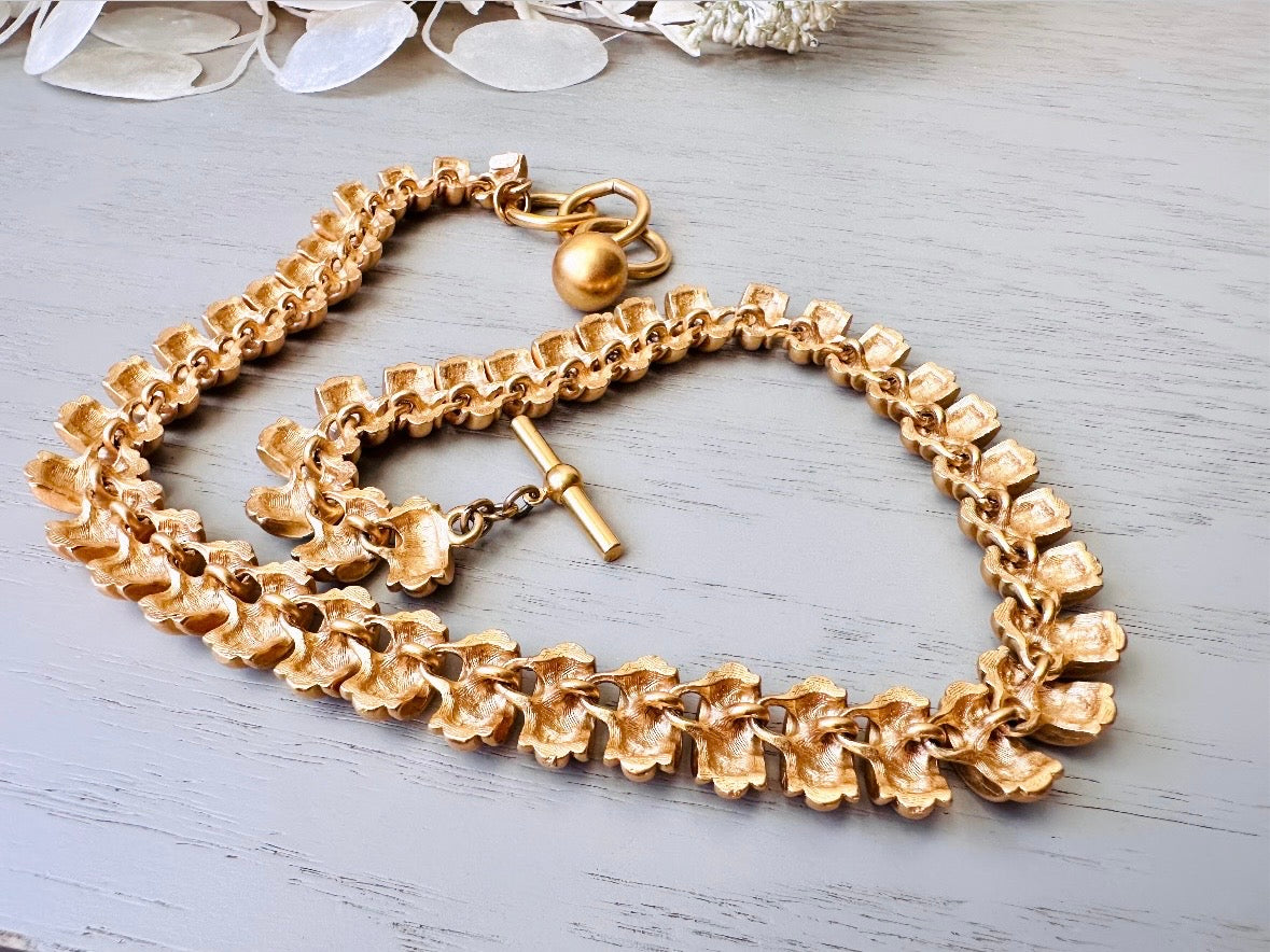 This vintage Anne Klein matte gold statement necklace is a beautiful classic satin gold collar necklace with articulated link segments.A signed AK piece, well known for superior quality and craftsmanship- this gold collar necklace is the perfect one to wear alone or pair with others for a spectacular stack. Toggle clasp at adjustable lengths. Back of necklace.