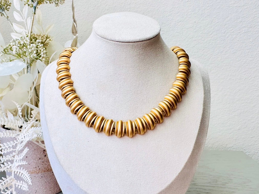 This vintage Anne Klein matte gold statement necklace is a beautiful classic satin gold collar necklace with articulated link segments.A signed AK piece, well known for superior quality and craftsmanship- this gold collar necklace is the perfect one to wear alone or pair with others for a spectacular stack. Toggle clasp at adjustable lengths.