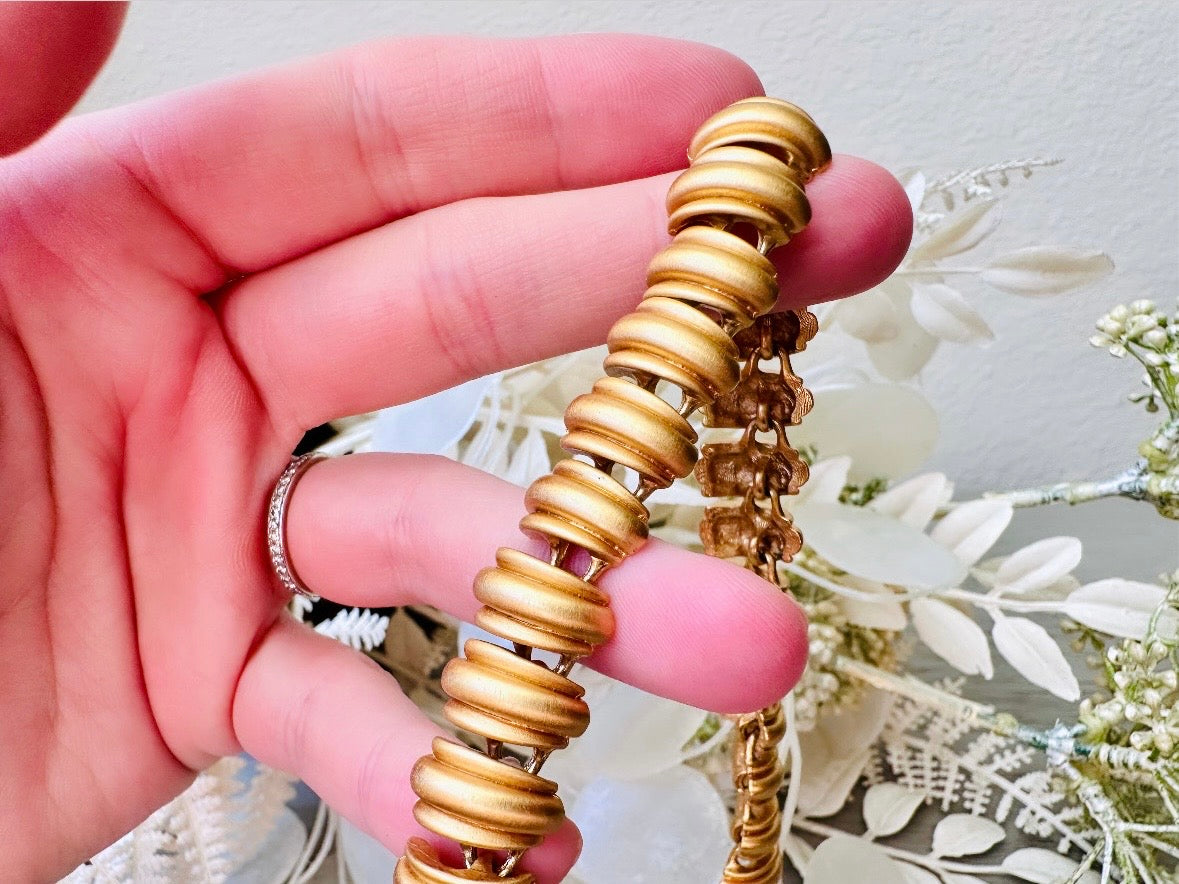 This vintage Anne Klein matte gold statement necklace is a beautiful classic satin gold collar necklace with articulated link segments.A signed AK piece, well known for superior quality and craftsmanship- this gold collar necklace is the perfect one to wear alone or pair with others for a spectacular stack. Toggle clasp at adjustable lengths.