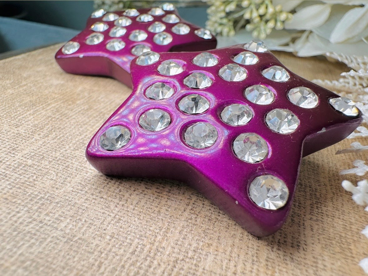 These oversized vintage purple star earrings are a highly collectible pair of 1980s statement earrings. These big and bold star earrings are a stunning shade of vibrant metallic magenta purple lucite with diamond rhinestone accents. Huge vintage star clip ons with major rockstar vibes. A fun 80s pair of unique earrings that you never knew you needed so badly.