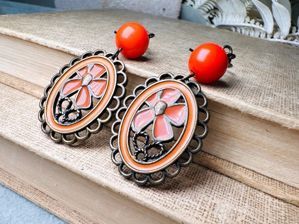 These orange flower enamel and bronze 70s vintage dangle earrings are fabulously funky. A lacey cameo featuring an orange enamel flower linked with a glossy orange bead. A very fun pair, the color is amazing- in great vintage condition, please view all pics.