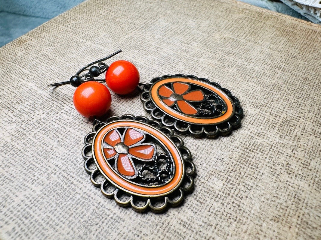 These orange flower enamel and bronze 70s vintage dangle earrings are fabulously funky. A lacey cameo featuring an orange enamel flower linked with a glossy orange bead. A very fun pair, the color is amazing- in great vintage condition, please view all pics.