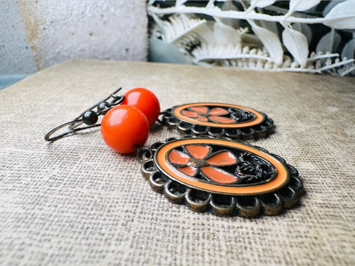 These orange flower enamel and bronze 70s vintage dangle earrings are fabulously funky. A lacey cameo featuring an orange enamel flower linked with a glossy orange bead. A very fun pair, the color is amazing- in great vintage condition, please view all pics.