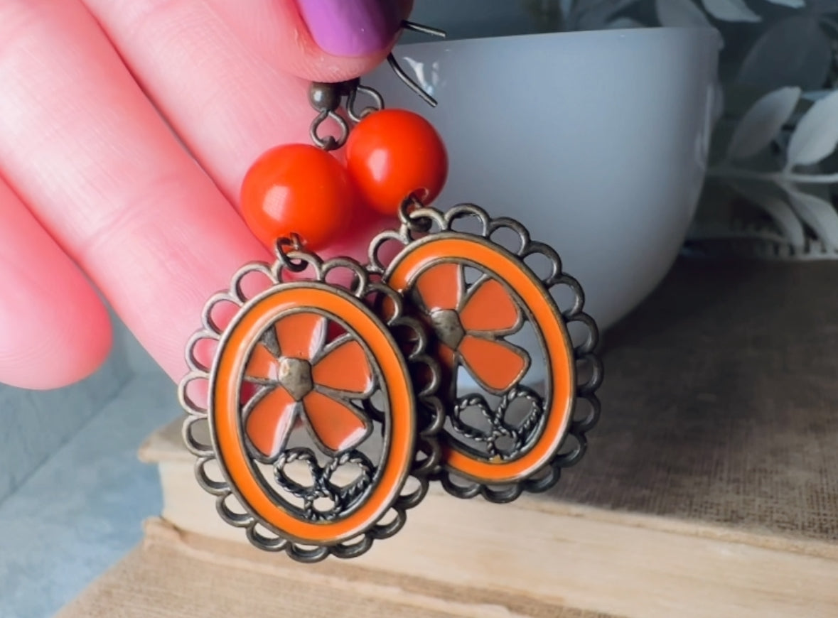 These orange flower enamel and bronze 70s vintage dangle earrings are fabulously funky. A lacey cameo featuring an orange enamel flower linked with a glossy orange bead. A very fun pair, the color is amazing- in great vintage condition, please view all pics.