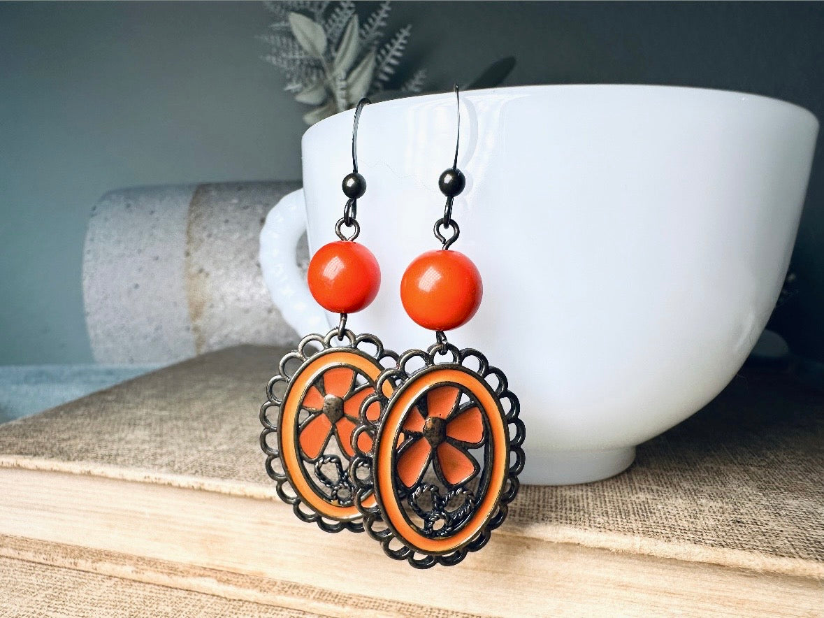 These orange flower enamel and bronze 70s vintage dangle earrings are fabulously funky. A lacey cameo featuring an orange enamel flower linked with a glossy orange bead. A very fun pair, the color is amazing- in great vintage condition, please view all pics.