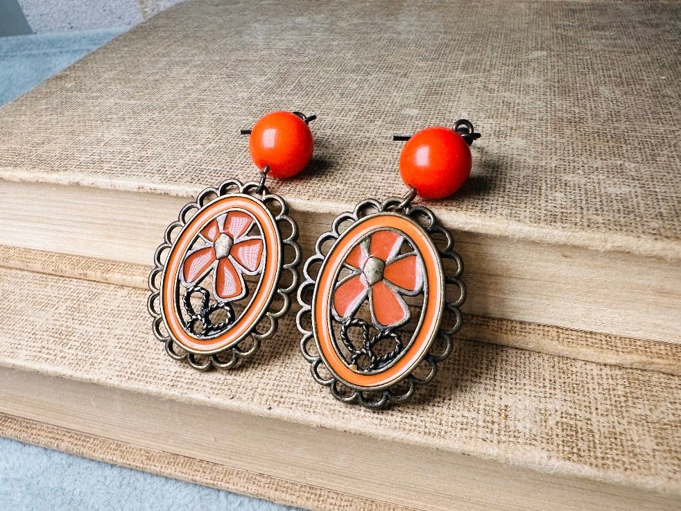 These orange flower enamel and bronze 70s vintage dangle earrings are fabulously funky. A lacey cameo featuring an orange enamel flower linked with a glossy orange bead. A very fun pair, the color is amazing- in great vintage condition, please view all pics.