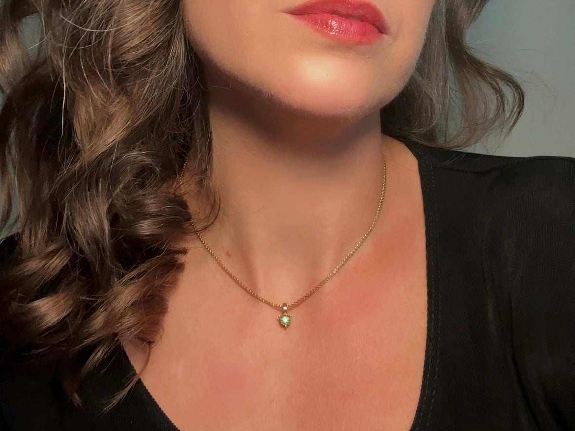 Close-up of a necklace with a pendant on a person wearing a black top.