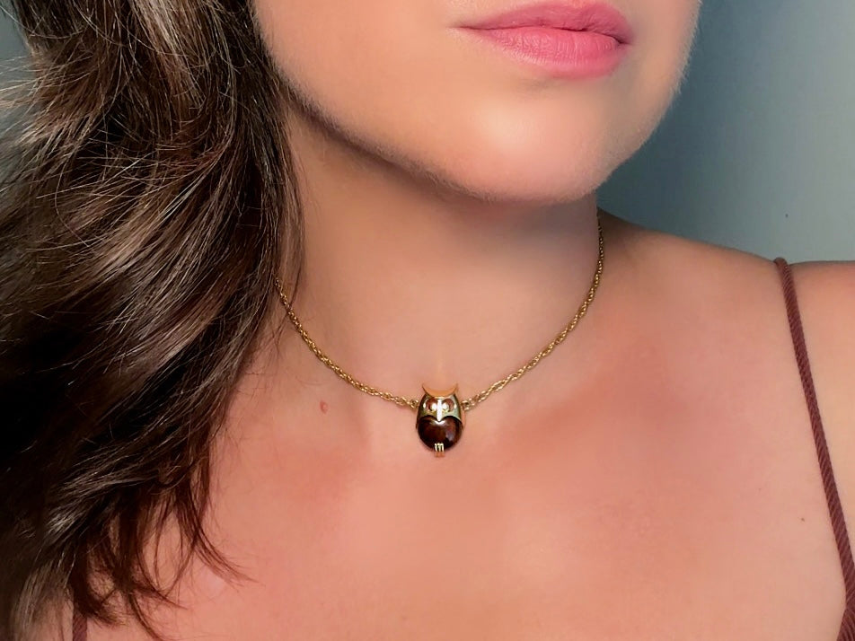 This vintage signed Crown Trifari Jelly Belly Owl necklace is a fantastic find! Gold tone twisted cable chain hosts a small intricate owl pendant with eye cut outs and a glowing chocolate brown lucite belly. These necklaces are highly collectible and hard to find with their original chains. From the 1960s. In great condition, with minimal wear from age, no major flaws to note.