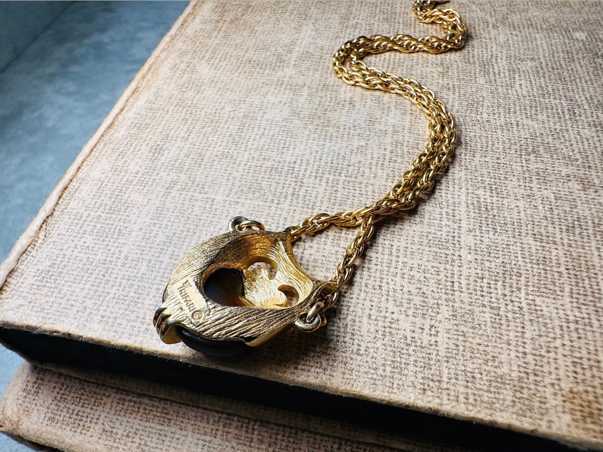 This vintage signed Crown Trifari Jelly Belly Owl necklace is a fantastic find! Gold tone twisted cable chain hosts a small intricate owl pendant with eye cut outs and a glowing chocolate brown lucite belly. These necklaces are highly collectible and hard to find with their original chains. From the 1960s. In great condition, with minimal wear from age, no major flaws to note.