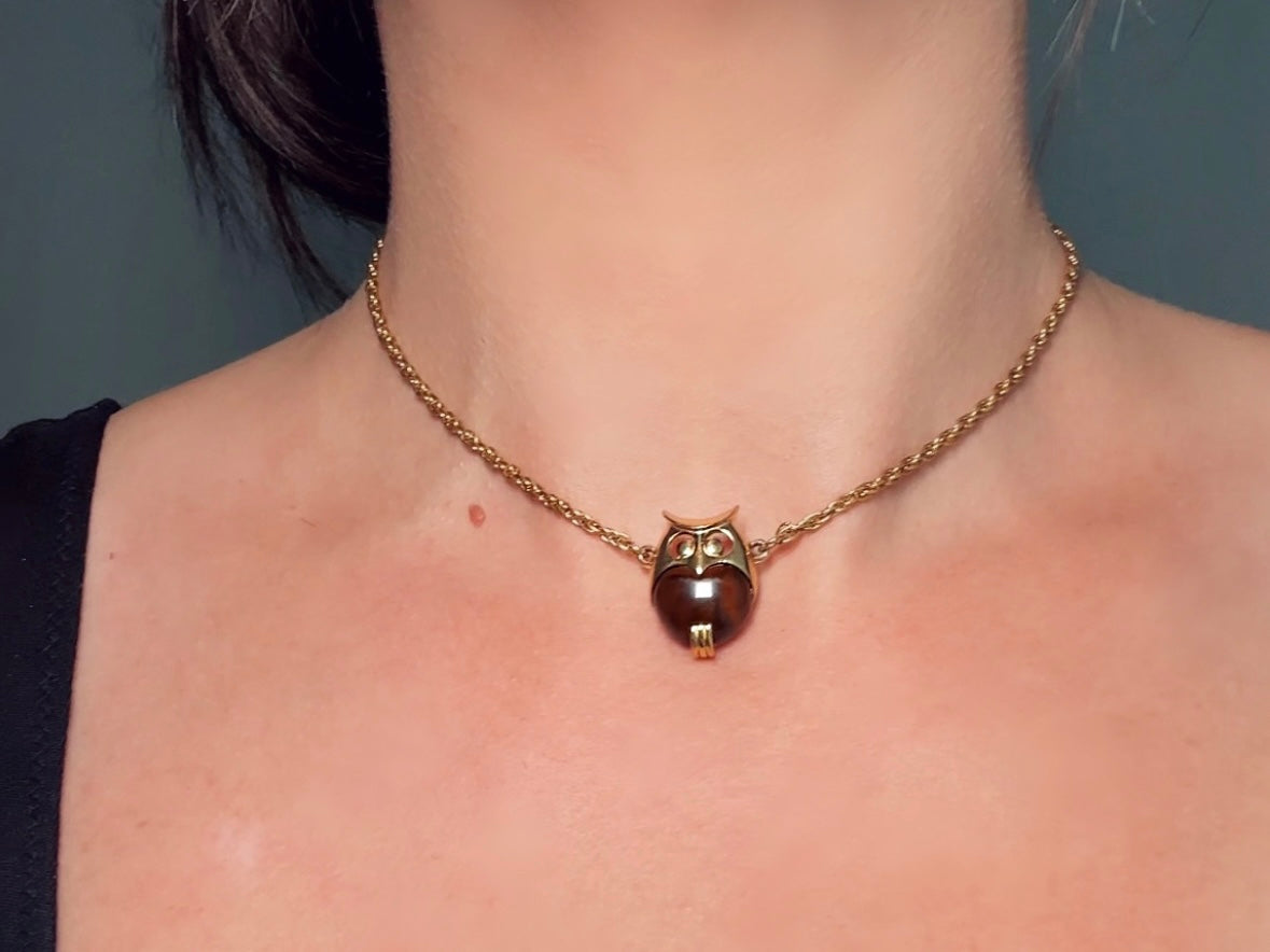 This vintage signed Crown Trifari Jelly Belly Owl necklace is a fantastic find! Gold tone twisted cable chain hosts a small intricate owl pendant with eye cut outs and a glowing chocolate brown lucite belly. These necklaces are highly collectible and hard to find with their original chains. From the 1960s. In great condition, with minimal wear from age, no major flaws to note.