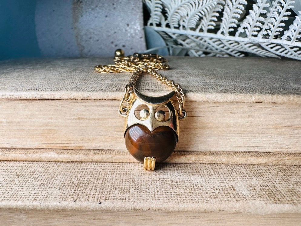 This vintage signed Crown Trifari Jelly Belly Owl necklace is a fantastic find! Gold tone twisted cable chain hosts a small intricate owl pendant with eye cut outs and a glowing chocolate brown lucite belly. These necklaces are highly collectible and hard to find with their original chains. From the 1960s. In great condition, with minimal wear from age, no major flaws to note.