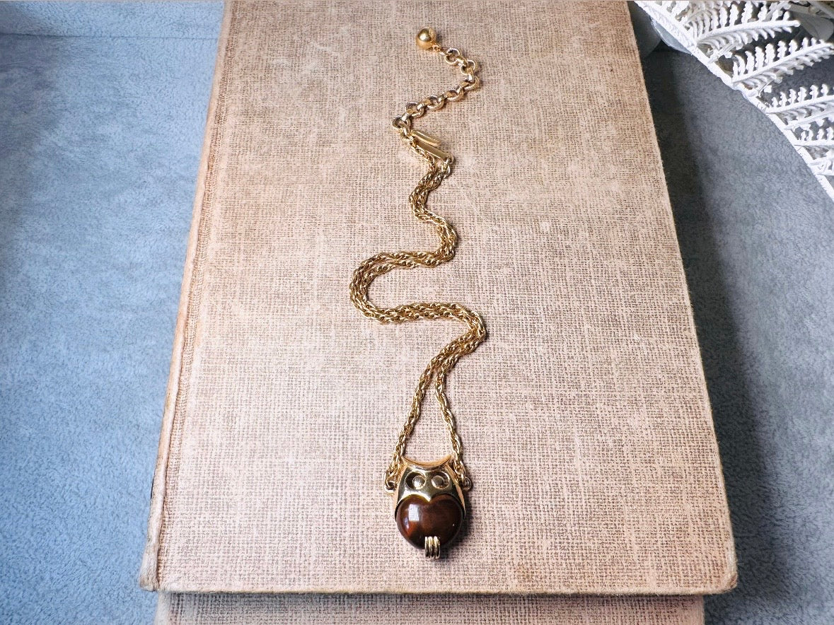 This vintage signed Crown Trifari Jelly Belly Owl necklace is a fantastic find! Gold tone twisted cable chain hosts a small intricate owl pendant with eye cut outs and a glowing chocolate brown lucite belly. These necklaces are highly collectible and hard to find with their original chains. From the 1960s. In great condition, with minimal wear from age, no major flaws to note.
