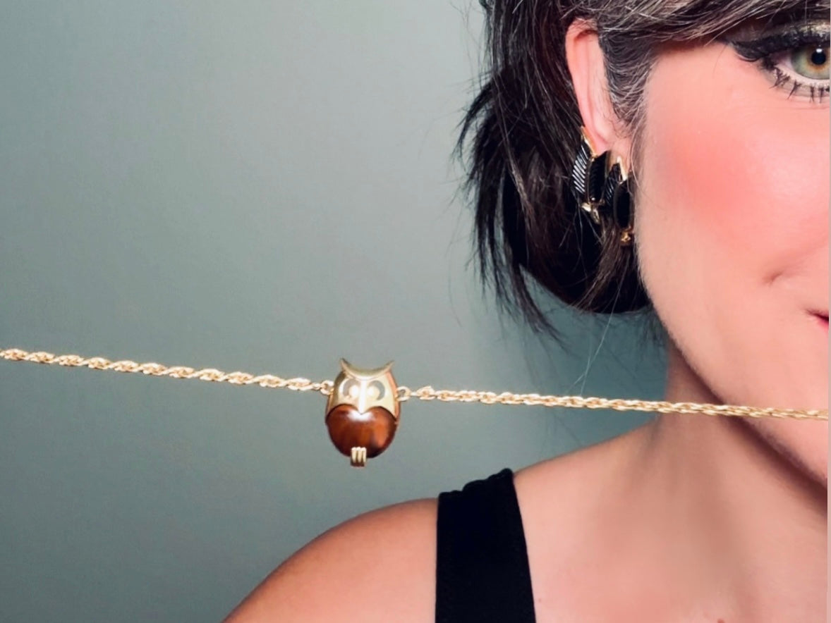 This vintage signed Crown Trifari Jelly Belly Owl necklace is a fantastic find! Gold tone twisted cable chain hosts a small intricate owl pendant with eye cut outs and a glowing chocolate brown lucite belly. These necklaces are highly collectible and hard to find with their original chains. From the 1960s. In great condition, with minimal wear from age, no major flaws to note.