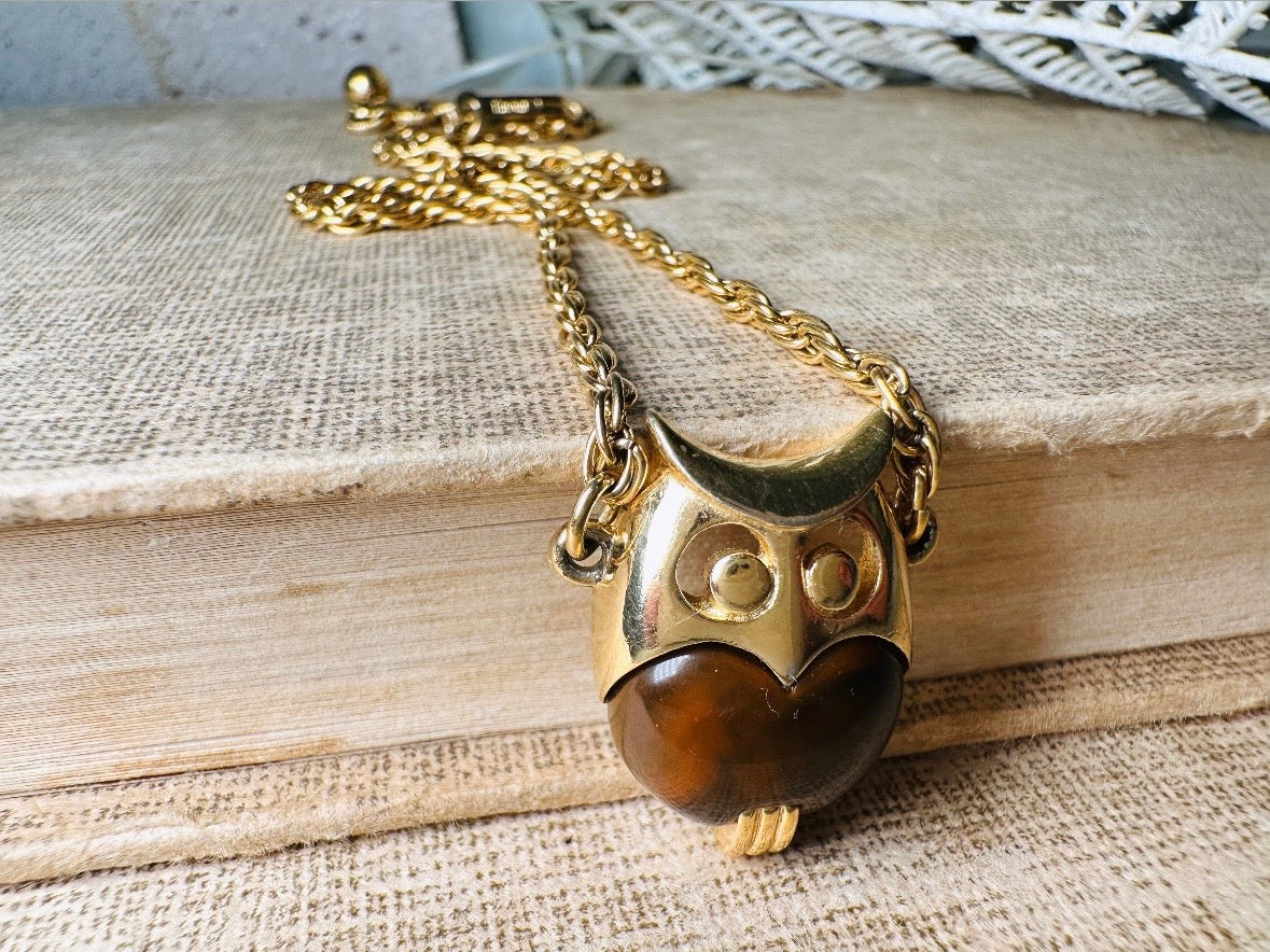 This vintage signed Crown Trifari Jelly Belly Owl necklace is a fantastic find! Gold tone twisted cable chain hosts a small intricate owl pendant with eye cut outs and a glowing chocolate brown lucite belly. These necklaces are highly collectible and hard to find with their original chains. From the 1960s. In great condition, with minimal wear from age, no major flaws to note.