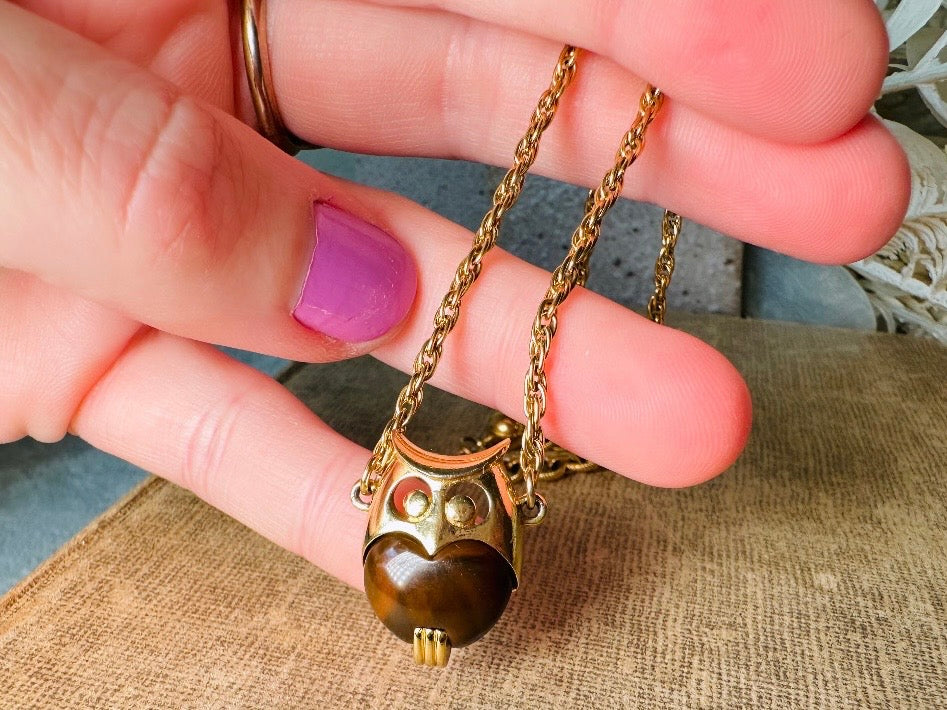 This vintage signed Crown Trifari Jelly Belly Owl necklace is a fantastic find! Gold tone twisted cable chain hosts a small intricate owl pendant with eye cut outs and a glowing chocolate brown lucite belly. These necklaces are highly collectible and hard to find with their original chains. From the 1960s. In great condition, with minimal wear from age, no major flaws to note.